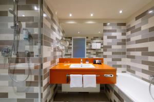 不莱梅赛马场大西洋饭店的浴室配有水槽、淋浴和浴缸。