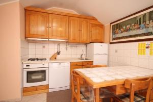 苏萨克Apartments with WiFi Susak, Losinj - 8047的厨房配有木制橱柜、桌子和冰箱。