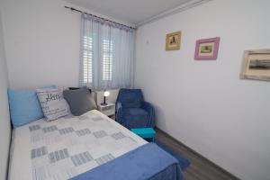 大洛希尼Apartments by the sea Veli Losinj, Losinj - 7959的一间卧室配有一张床和一张蓝色椅子