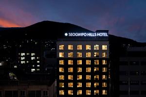 西归浦市Seogwipo Hills Hotel的一座建筑物,上面有夜间标志