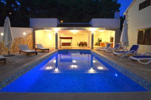 普利兹巴Seaside family friendly house with a swimming pool Brna - Vinacac, Korcula - 9266的夜晚在后院的蓝色海水游泳池