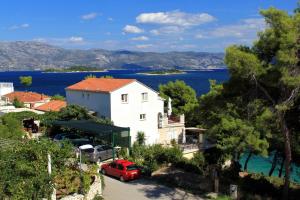 鲁巴达Apartments by the sea Lumbarda, Korcula - 9172的前面有一辆红色汽车的房屋