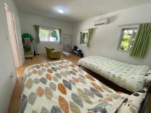 今归仁村Fukugi INN的一间卧室设有两张床、一把椅子和窗户。