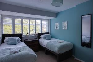 Sunbury CommonSAXON ROAD - A 3 Bedroom House with Garden by Prestigious Stays - Includes Wifi, Netflix & Amazon Alexa的配有两张床铺的蓝色墙壁和窗户