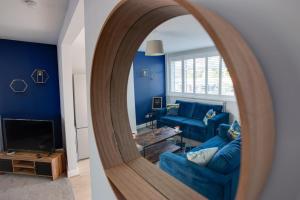 Sunbury CommonSAXON ROAD - A 3 Bedroom House with Garden by Prestigious Stays - Includes Wifi, Netflix & Amazon Alexa的客厅设有蓝色的墙壁和镜子
