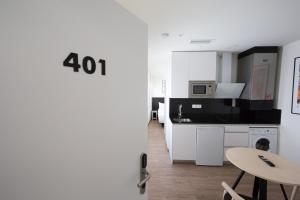 马德里Apartamentos Centro Jardines的一间厨房,内设白色橱柜和一张桌子