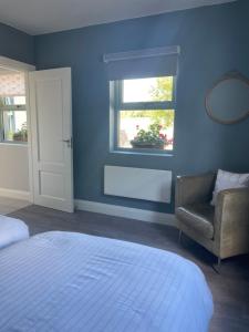 香农河畔卡里克The Potters Lodge的蓝色的卧室设有床、椅子和窗户