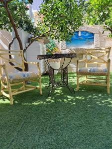 奥尔比亚Zia Mia B&b的庭院配有两把椅子、一张桌子和一张桌子以及长凳。