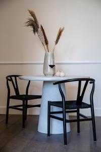 奥斯坦德Villa Ostinato的一张桌子,上面有两把椅子和一个花瓶