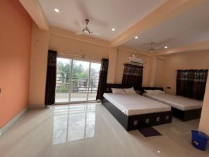 德奥加尔Hotel Krishna Paradise的一间卧室设有两张床和大窗户