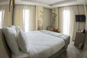 伊斯坦布尔佩科酒店的卧室配有一张带白色床单和枕头的大床。