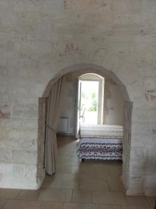 洛科罗通多I trulli di Nonno Battista的带拱门、床和窗户的客房