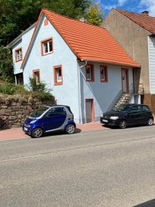 瓦尔德-米谢尔巴赫Ferienhaus zum Ulfenbachtal的两辆汽车停在白色房子前面