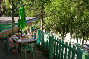 Brassacvillage vacances du camboussel的一群人坐在一张桌子上,拿着一把绿伞