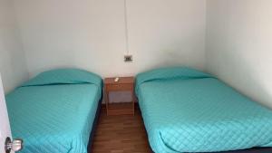 塔尔塔尔Hostal Viña Del Mar的小型客房的两张床,设有床头柜