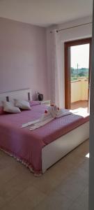 卡斯塔涅托卡尔杜奇Agriturismo IL VECCHIO OLIVO的一间卧室配有一张带紫色床单的床和窗户。
