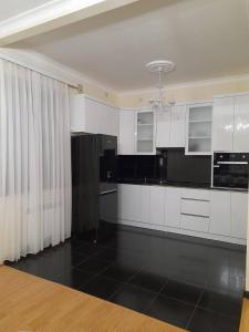 叶海格纳佐尔D&G guest house的厨房配有白色橱柜和黑色地板
