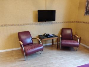 ÖrsundsbroHustugu Gård的一间设有两把椅子和一张桌子的等候室以及一台电视