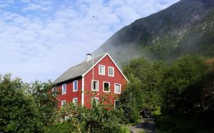 ÅrdalLake View Holiday Stay in Jølster的山前的一座红色大房子