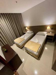 里约热内卢Apto tipo Flat Midas Riocentro - Barra da Tijuca- Barra olímpica的酒店客房设有两张床和一张桌子。