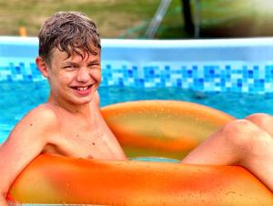 瓦古夫Agroturystyka "Zielone Zacisze"的坐在游泳池里橘色木筏上的年轻人