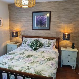 卡尔斯Maggie's Place in Cowes的一间卧室配有一张带2个床头柜和2盏灯的床。