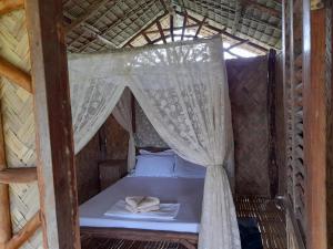 爱妮岛Erlittop Garden Eco Lodge的稻草小屋内的一张床位,配有蚊帐