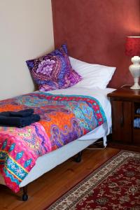 Gellibrand盖利布兰德河画廊度假屋的床上有色彩缤纷的毯子和枕头