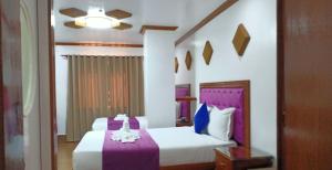 独鲁万CLN精品酒店的一间卧室配有两张紫色和白色床单