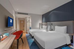兰州兰州新区智选假日酒店的酒店客房,设有两张床和一张红色椅子