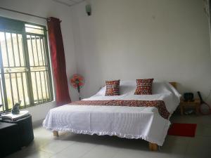 基加利Villa Kikiriki的卧室配有带枕头的白色床和窗户。