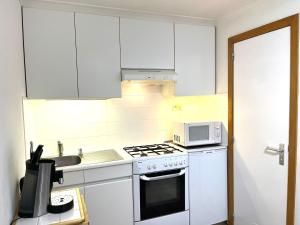 布兰肯贝赫Chez’ Elle的厨房配有白色橱柜、炉灶和微波炉。