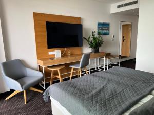 科沃布热格Seaside Park Hotel Kołobrzeg apartament 27 metrów szczęścia的一间卧室配有一张桌子、一台电视和一张床