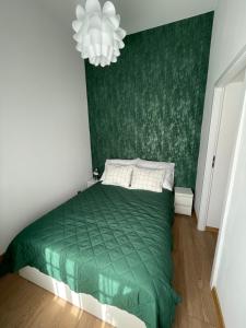 奥斯特罗达Mini apartament Ostróda的一间卧室配有一张绿色的床和吊灯。