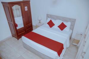 基加利Martin Aviator Hotel的一间卧室配有一张带红色枕头的大床