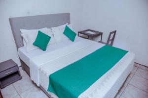 基加利Martin Aviator Hotel的一间卧室配有一张带绿色枕头的大床