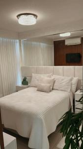 戈亚尼亚Lindo flat Easy Life的卧室配有一张带吊灯的大型白色床。