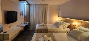 纳塔尔Flat Maravilhoso na praia - Ilusion Hotel的酒店客房设有两张床和电视。