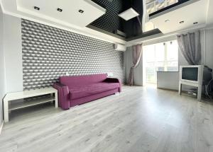 基辅Квартира напротив Дрим-Тауна的客厅配有紫色沙发和电视