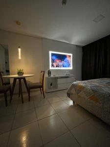 萨尔瓦多Suíte luxo com tela de cinema no América Towers Studio Residence的一间卧室配有一张床、一张桌子和一台电视。