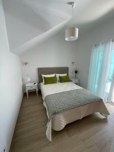 蒙希克Alojamento S. Gabriel 1的白色卧室配有一张带绿色枕头的大床