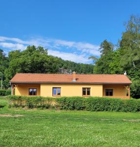 比托福泰萨如小屋酒店的一座黄色的房屋,绿地和树木