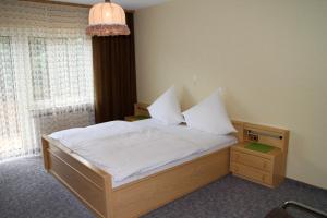 Ober-KainsbachGasthaus Zum Hohenstein的一间卧室配有一张带白色床单的床和一扇窗户。