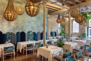 德拉塞尔瓦港克里斯托港酒店暨Spa的餐厅设有白色的桌椅和吊灯。