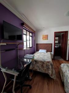 昆卡Casatodosantos的一间卧室配有一张床、一张书桌和一台电视。