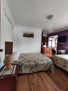 昆卡Casatodosantos的一间卧室配有两张床和一张带台灯的桌子