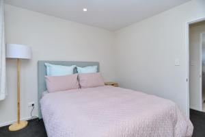 基督城Thomas Townhouse - Christchurch Holiday Homes的白色卧室配有白色床和粉红色枕头