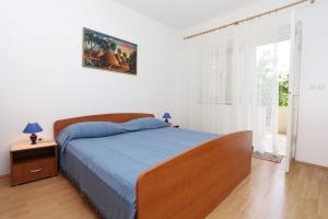 维甘Apartment Viganj 10116d的一间卧室配有一张带蓝色棉被的床