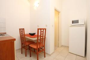 维甘Apartment Viganj 10116d的厨房配有桌子、两把椅子和微波炉
