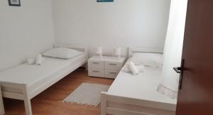 泰斯Seaside holiday house Nemira, Omis - 9504的配有白色墙壁和木地板的客房内的两张床